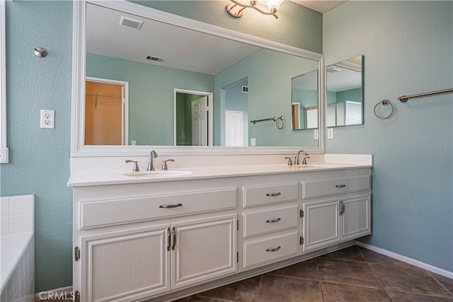 bathroom with a tub, tile patterned floors, and vanity