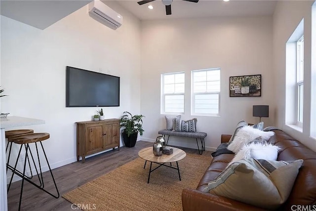 living room featuring a wall mounted air conditioner, dark hardwood / wood-style floors, ceiling fan, and a wealth of natural light