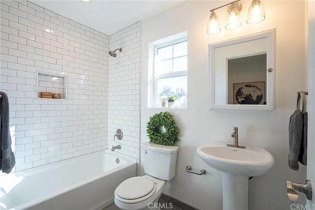 bathroom with tiled shower / bath combo and toilet