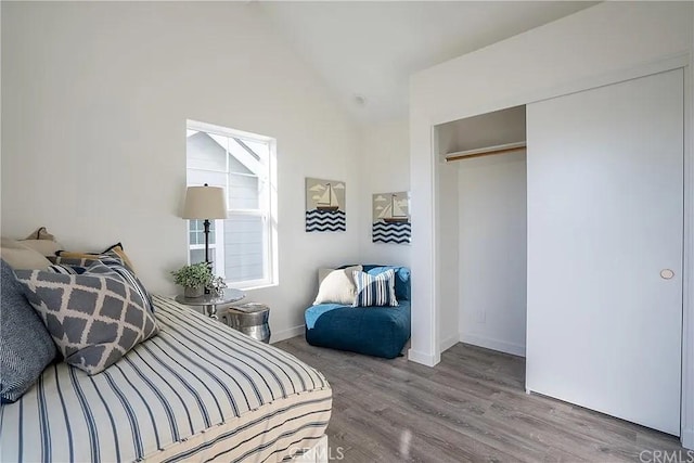 bedroom with lofted ceiling, light wood-type flooring, and a closet