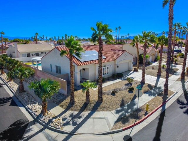 mediterranean / spanish home featuring solar panels and a garage