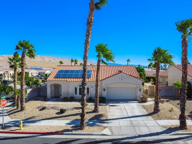 mediterranean / spanish home with a mountain view, a garage, and solar panels