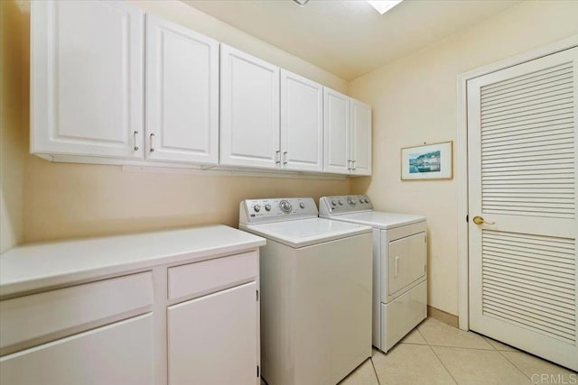 washroom with cabinets, washing machine and dryer, and light tile patterned flooring