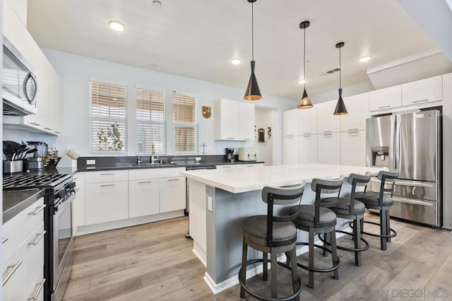 kitchen with pendant lighting, stainless steel appliances, and white cabinetry