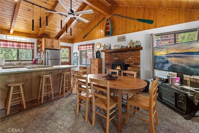 carpeted dining area with beamed ceiling, plenty of natural light, and wood ceiling