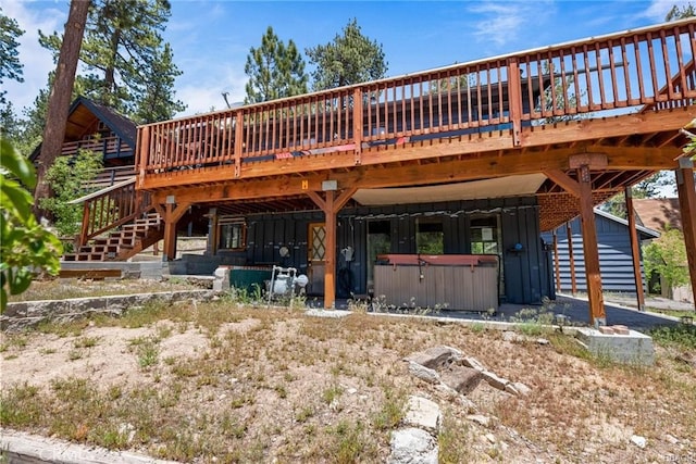 rear view of property with a wooden deck and a hot tub