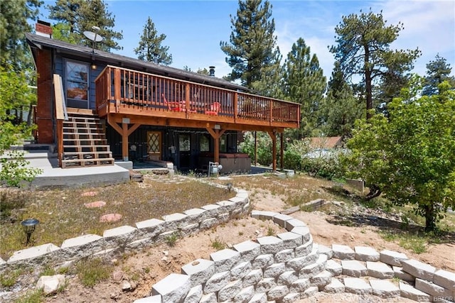 rear view of house with a jacuzzi and a wooden deck