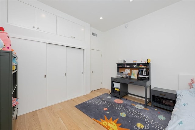 bedroom with light hardwood / wood-style floors and a closet