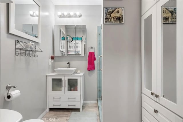 bathroom with hardwood / wood-style floors, vanity, toilet, and a shower with shower door