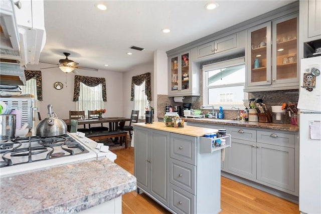 kitchen featuring tasteful backsplash, gray cabinets, ceiling fan, and light wood-type flooring