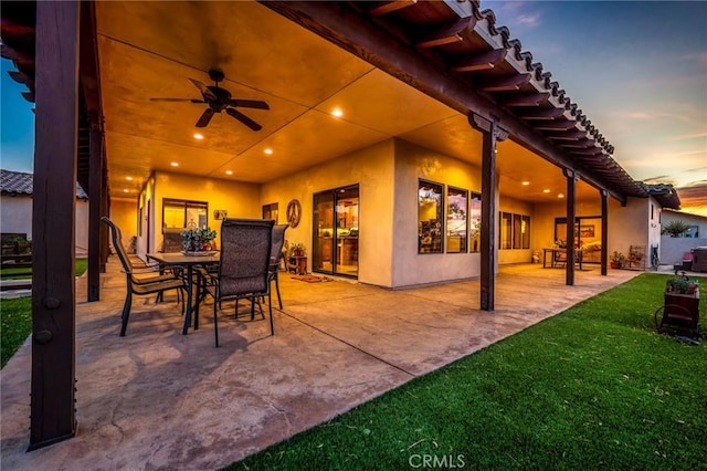 61138 Onaga Trl, Joshua Tree, CA 92252 - patio terrace at dusk featuring a ceiling fan, a patio, a yard, and outdoor dining space