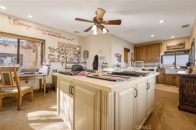 kitchen featuring light carpet, ceiling fan, sink, and a center island