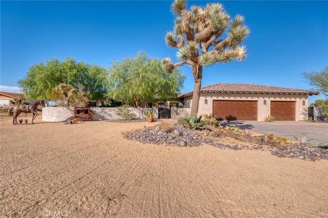 61138 Onaga Trl, Joshua Tree, CA 92252 - view of front facade with stucco siding, a garage, concrete driveway, and a tiled roof