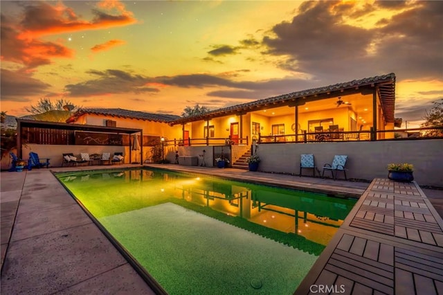 pool at dusk with a patio area