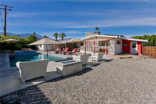 rear view of property featuring a fenced in pool, a patio area, and an outdoor fire pit