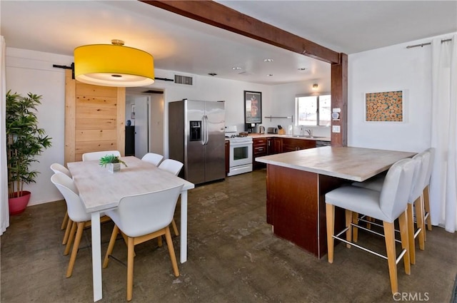 kitchen featuring a kitchen breakfast bar, stainless steel fridge, a barn door, white range oven, and kitchen peninsula