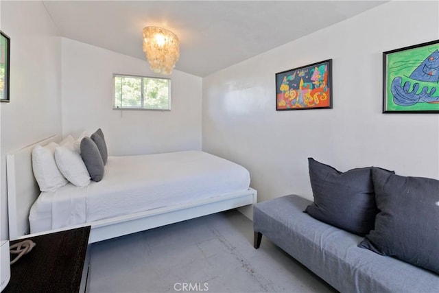 bedroom featuring concrete flooring and a notable chandelier