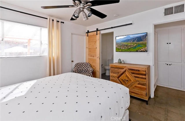 bedroom with ceiling fan, a barn door, and ensuite bathroom