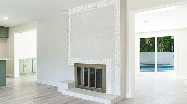 unfurnished living room featuring light wood-type flooring and a large fireplace