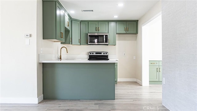 kitchen featuring green cabinets, light wood-type flooring, electric stove, and sink