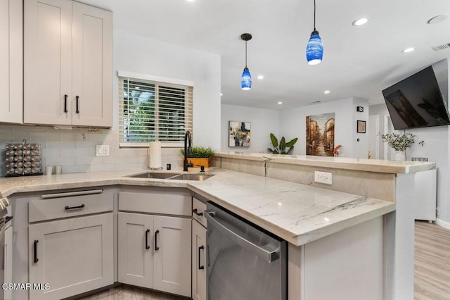 kitchen with sink, light stone counters, decorative light fixtures, stainless steel dishwasher, and backsplash