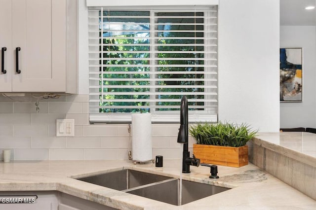 interior details with white cabinetry, sink, and tasteful backsplash