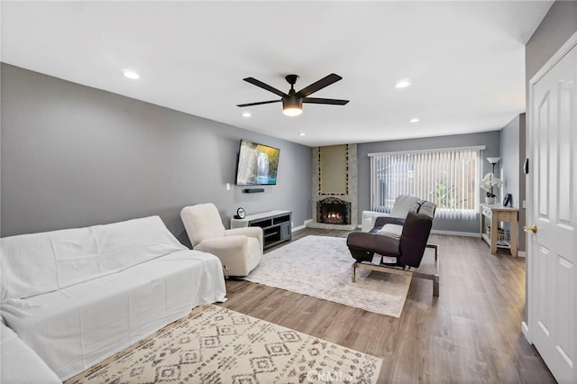 living room with ceiling fan, a fireplace, and hardwood / wood-style flooring