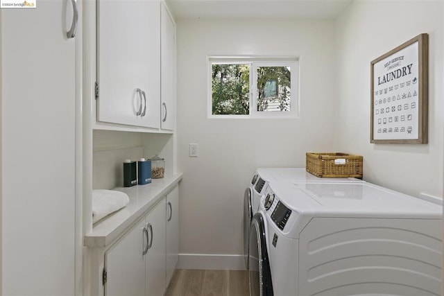 laundry room with hardwood / wood-style flooring, cabinets, and washing machine and dryer