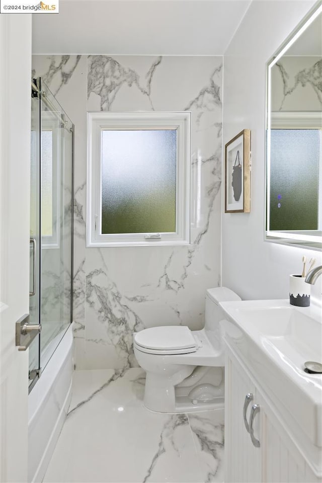 full bathroom with vanity, bath / shower combo with glass door, and toilet