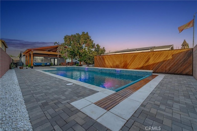 pool at dusk featuring a patio area