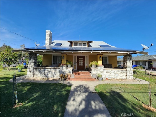 view of front of house with covered porch, a front yard, and solar panels