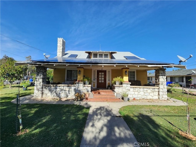 view of front facade with a porch, a front yard, and solar panels