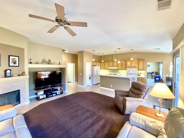 tiled living room featuring ceiling fan, lofted ceiling, and a tile fireplace