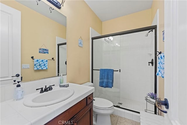 bathroom with tile patterned flooring, vanity, toilet, and a shower with shower door