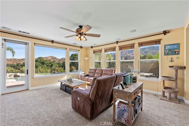 living room with a mountain view, ceiling fan, and light carpet