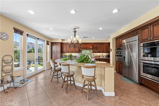 kitchen featuring light stone countertops, a center island, french doors, stainless steel appliances, and pendant lighting