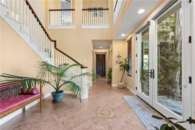 foyer entrance featuring a towering ceiling and light tile patterned floors