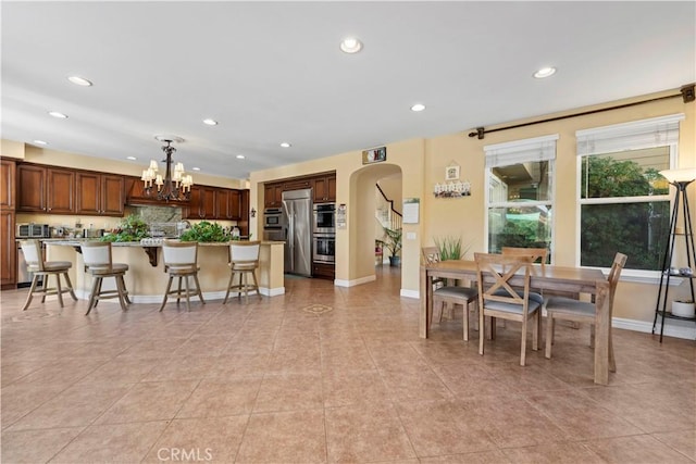 kitchen featuring a kitchen bar, appliances with stainless steel finishes, a chandelier, a center island, and hanging light fixtures