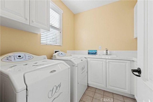 laundry room with light tile patterned flooring, cabinets, separate washer and dryer, and sink