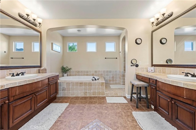 bathroom featuring tile patterned floors, plenty of natural light, vanity, and tiled bath