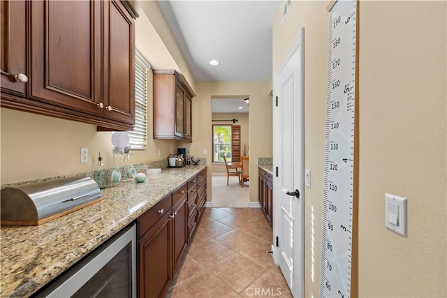 kitchen featuring light stone counters, light tile patterned floors, and wine cooler