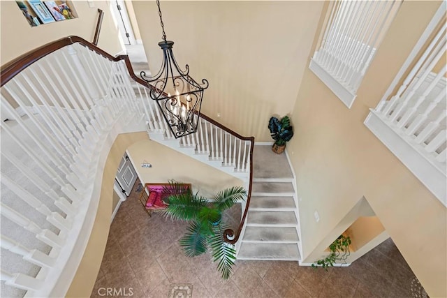 staircase featuring a chandelier, a towering ceiling, and tile patterned flooring