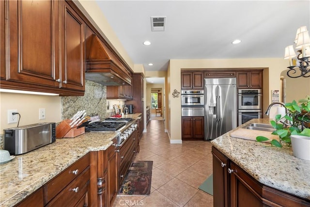 kitchen with light stone counters, light tile patterned floors, premium range hood, and appliances with stainless steel finishes