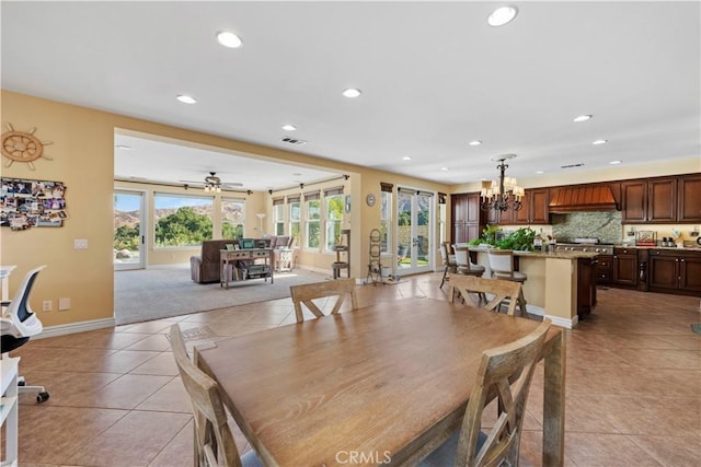 dining room with light tile patterned floors and ceiling fan with notable chandelier