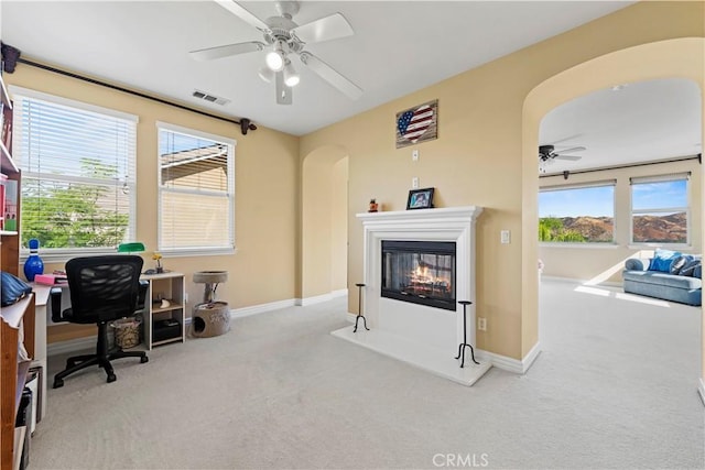 office featuring light carpet, ceiling fan, and a healthy amount of sunlight