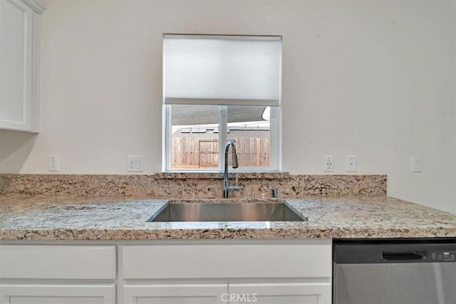 kitchen with dishwasher, white cabinets, light stone counters, and sink