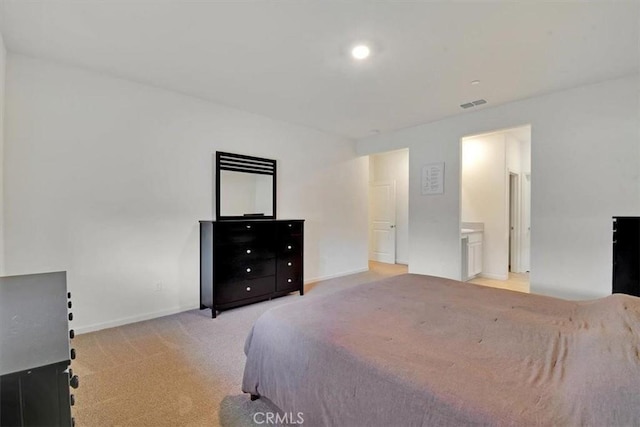 bedroom featuring ensuite bathroom and light carpet