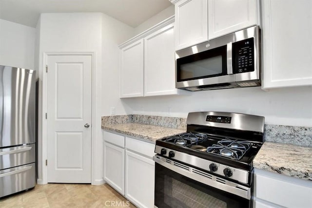 kitchen featuring white cabinets, appliances with stainless steel finishes, and light stone countertops