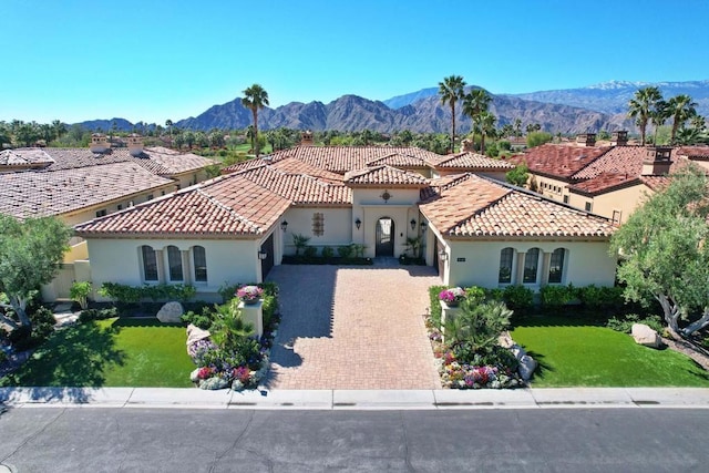 mediterranean / spanish home with a mountain view and a front lawn