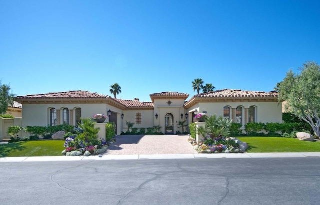 mediterranean / spanish-style home featuring a garage and a front yard